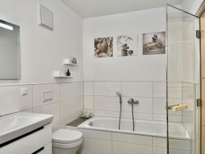 een witte badkamer met een bad en een toilet bij Sonnenweg 11 in Heringhausen +28 foto's