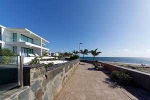 a person sitting on a bench next to the beach at Amapola Palms - recién reformado, frente al mar in San Agustin