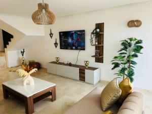 a living room with a couch and a tv on the wall at Ocean View Duplex & Golf, Taghazout Bay in Tamraght Ouzdar