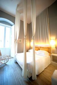 1 dormitorio con 1 cama blanca con cortinas y silla en Le Stanze di Corteinfiore, en Trani