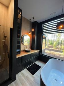 un bagno con vasca, lavandino e finestra di Brand New Black Fox Cabin with Private Nordic Spa a Sprucedale Altre 29 foto