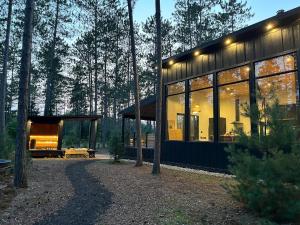 una casa nel bosco con molte finestre di Brand New Black Fox Cabin with Private Nordic Spa a Sprucedale