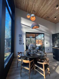 una sala da pranzo con tavolo, sedie e finestre di Brand New Black Fox Cabin with Private Nordic Spa a Sprucedale