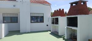an outside view of a white building with two windows at El nuevo amanecer mar de ajó in Mar de Ajó
