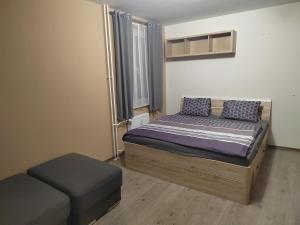 a small bedroom with a bed and a ottoman at Byteček in Karlovy Vary