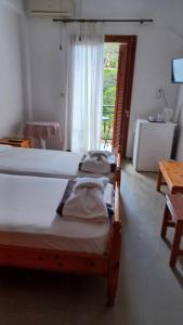 a bedroom with a bed and a table and a window at Hotel Rena in Agios Kirykos