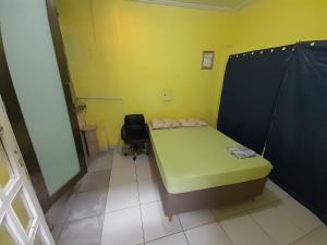 a small room with a green bed and a chair at RD suítes 1 in Guarujá