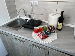 um balcão de cozinha com um lavatório e algumas chávenas e uma garrafa de vinho em Konaciste Napredak em Kraljevo