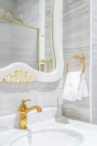 a bathroom sink with a gold faucet and a mirror at Paix in Paris