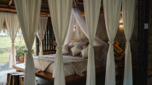 a bedroom with a canopy bed with white curtains at Cabaña Los Matapalos en Yopal WISIRARE LODGE 6 personas in Yopal