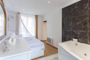 a bedroom with a white bed and a sink and a tub at L'amour vrai - Love room -T2 Elégant et Romantique in Abbeville