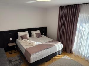 a bedroom with a large bed and a large window at Marmotta Paltinis in Păltiniş