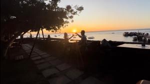 a group of people standing on the beach watching the sunset at Apartamento praça Morro de São Paulo in Cayru