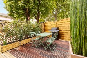 a patio with a table and chairs on a wooden deck at Au coeur de Marlotte in Bourron-Marlotte