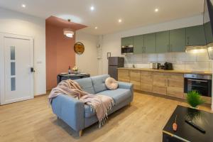a living room with a blue couch and a kitchen at La chute des feuilles - Lit double- T2 Hyper centre in Abbeville