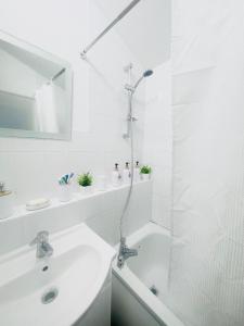 a white bathroom with a shower and a sink at Cozy Urban Scape in London