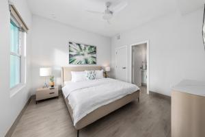 a white bedroom with a large bed and a window at Affordable Luxury Apartments, 3 Min to Beach in West Bay +22 photos
