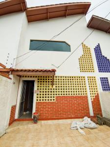 a white and red house with a brick wall at Casa de Praia Aconchegante in Peruíbe +5 photos