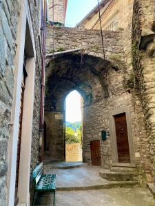 an archway in a stone building with a green bench at La Casa del Voltone in Pontremoli