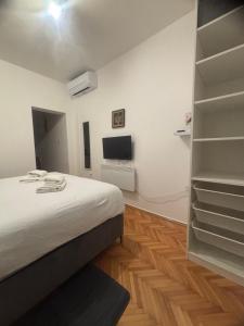 Schlafzimmer mit einem Bett, einem TV und Regalen in der Unterkunft Morosini Apartments in Biograd na Moru