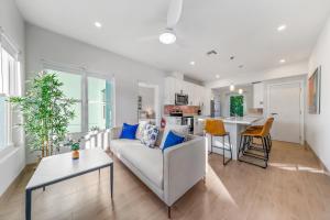 a living room with a white couch and a kitchen at Affordable Luxury Apartments, 3 Min to Beach in West Bay