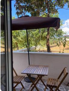 Una mesa de picnic y dos sillas bajo una sombrilla. en Appartamenti Palinuro Isca, en Palinuro