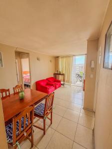 拉塞雷纳Departamento a 5 minutos de la playa的客厅里有一张桌子和一张红色沙发