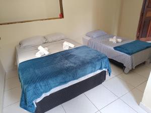 two beds in a room with towels on them at Suíte Pousada Rio das Ostras VII in Rio das Ostras