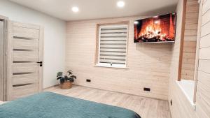 a bedroom with a fireplace and a tv on the wall at Butas ant ežero kranto in Telšiai