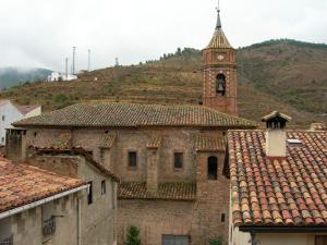 un antiguo edificio con una torre de reloj en una colina en Apartamentos Turísticos Rosario en Camarena de la Sierra