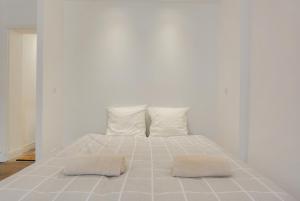 a white bed with two pillows on top of it at Appartement place Stanislas 1er in Nancy