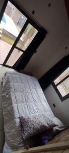 a bed in a room with two windows at Casa El Aromito Anisacate in Villa Anizacate