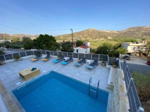 a swimming pool with chaises and chairs on a roof at Maistro Suites With Pool, Matala in Matala