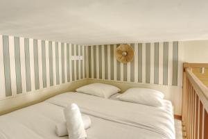 ein Bett mit zwei Kissen und einer Uhr an der Wand in der Unterkunft Le Saint Julien in Versailles