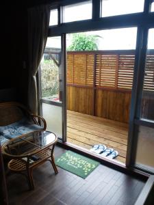 a room with a balcony with a chair and a window at Guest House Miyakojima in Miyako-jima