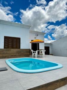 a large swimming pool with a table and an umbrella at Casa Beira Mar com Piscina in Rio Grande