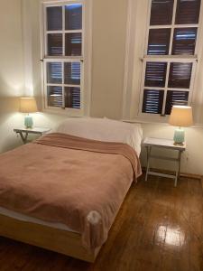 a bedroom with two tables and a bed with two windows at Maris Greek House in Konak