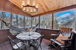 a porch with a table and chairs and a chandelier at Lakefront Movie Theater, Hot Tub, Arcade, Boats in Gouldsboro