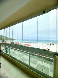a view of a beach from a building with large windows at Apartamento Luxo Vista Mar Andrei Noriller in Arraial do Cabo