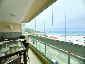 a room with a view of the beach from a large window at Apartamento Luxo Vista Mar Andrei Noriller in Arraial do Cabo