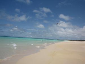 a person is flying a kite on a beach at Guest House Miyakojima in Miyako-jima