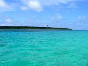 an island in the ocean with a kite in the sky at Guest House Miyakojima in Miyako-jima