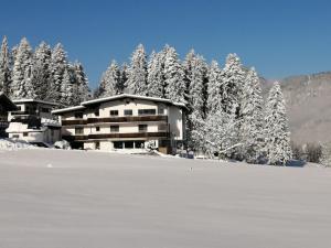 un edificio di fronte a una foresta innevata di Landhaus Argus a Fügenberg