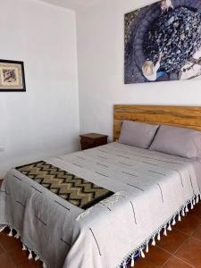 a bed in a bedroom with a painting on the wall at Casa Aida in San Pablo Villa de Mitla