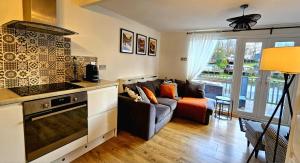 a living room with a couch and a kitchen at Dillons Lakeside Lodge in Caeathro