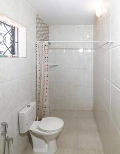 a white bathroom with a toilet and a shower at Zyon's Hideaway Goa in Calangute +24 photos