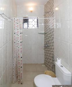 a white bathroom with a shower and a toilet at Zyon's Hideaway Goa in Calangute
