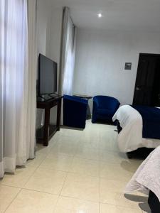 a bedroom with a bed and blue chairs and a television at Suite Los Angeles in Tecozautla +40 photos