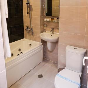a bathroom with a tub and a toilet and a sink at Hotel Bulgaria in Kŭrdzhali