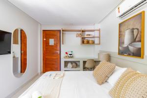 a bedroom with a white bed and a wooden door at Pousada Praiana in Porto De Galinhas